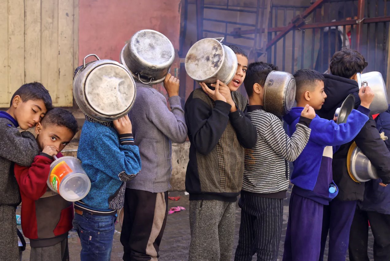 2023年12月14日，在加沙地帶南部的拉法，隨著以色列和哈馬斯之間的沖突持續(xù)，巴勒斯坦兒童拎著鍋排隊領(lǐng)取慈善廚房烹制的食物，沖突繼續(xù)導(dǎo)致糧食供應(yīng)短缺。