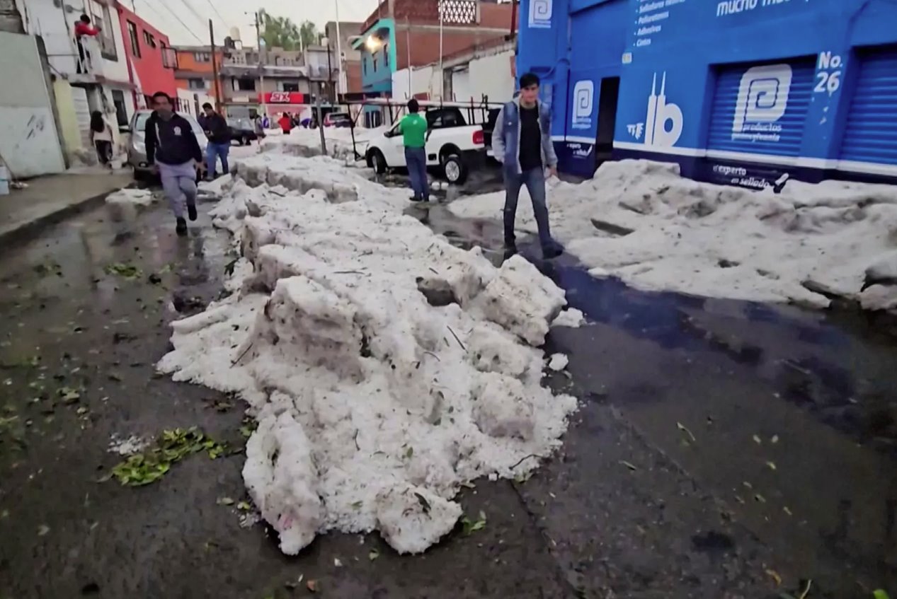 2024年5月24日，墨西哥普埃布拉，熱浪中的冰雹過后，人們在厚冰旁行走。