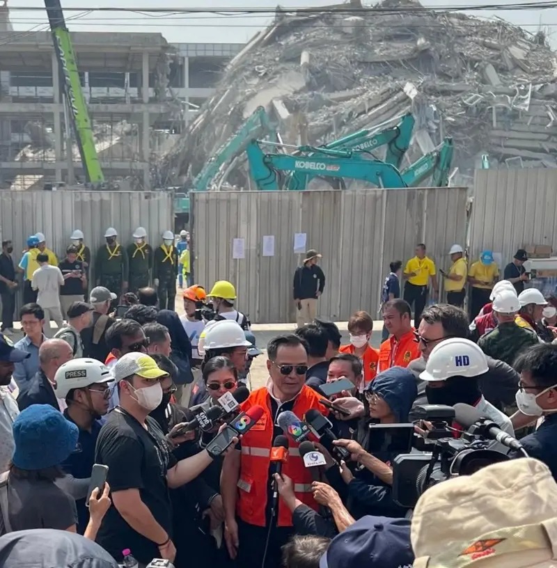 泰國(guó)副總理站在倒塌建筑的廢墟前，被記者包圍。